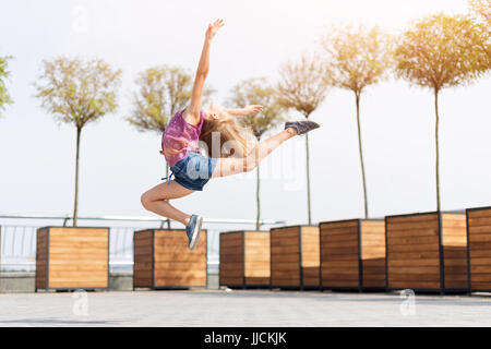 Aktives Kind Mädchen Turnerin springen oder tanzen auf der Straße. Junges Mädchen Acrobat. Das Mädchen beschäftigt sich mit Gymnastik. Stockfoto