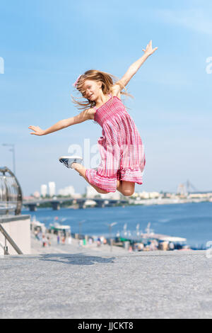 Aktives Kind Mädchen Turnerin springen oder tanzen auf der Straße. Junges Mädchen Acrobat. Das Mädchen beschäftigt sich mit Gymnastik. Stockfoto