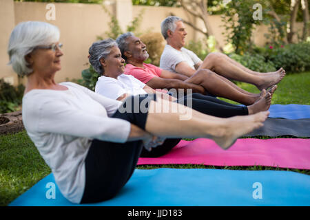 Senioren Freunde tun stretching-Übung im sitzen auf den Matten im Park gewidmet Stockfoto