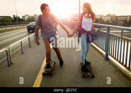 Junges attraktives Paar Skateboard fahren und Spaß haben Stockfoto