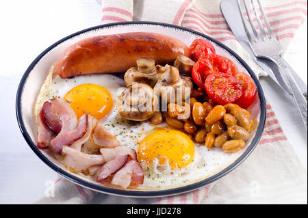 Englisches Frühstück - gebratenes Ei, Bohnen, Tomaten, Champignons, Speck und Wurst. Stockfoto