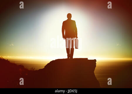 Silhouette Mann mit Aktenkoffer während des Gehens gegen die malerische Aussicht auf Berg Meer gegen Himmel Stockfoto