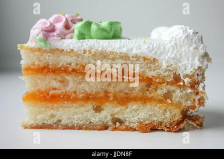 Stück Kuchen mit rosa Blume. Schuss auf weißem Hintergrund hautnah. Foto für Ihr Design. Stockfoto