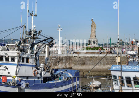 Angeln, Hafen und Statue der Virgen del Carmen in der Mole am unteren Rand der Ortschaft Santurtzi, Bilbao, Vizcaya, Baskenland, Spanien Stockfoto