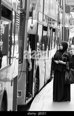 Eine junge muslimische Frau scheint Schwierigkeiten machen auf einem Londoner bus Stockfoto