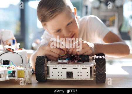 Angenehme junge anschließen Kabel in Roboterfahrzeug Stockfoto