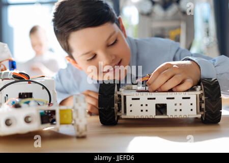 Inspiriert Student einen Teil in Roboterfahrzeug anpassen Stockfoto