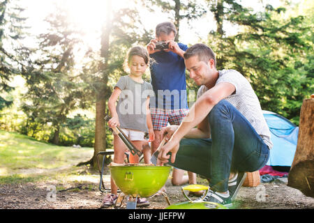 Familie camping im Wald, Kochen von Fleisch auf Grill. Stockfoto