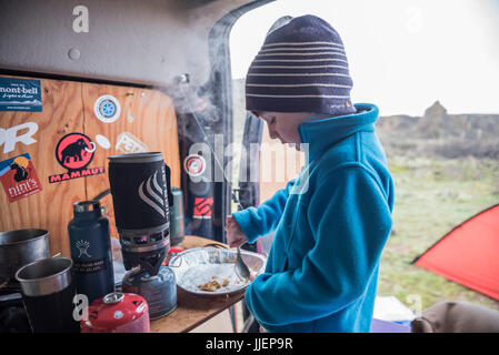 Ein kleiner Junge beendet die letzten paar Krümel Tortenboden bei einem camping-Ausflug. Stockfoto