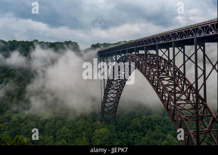 Nebel-Wirbel um die Brücke über den New River Gorge und New River, in den Appalachen in der Nähe von Fayetteville, WV.  Die Brücke, Baujahr 1977, ist die größte Spannweite Stahlbrücke in der westlichen Hemisphäre und die dritte höchste in den USA.  Es erstreckt sich über den New River National River, Bestandteil der US-Park-Service. Stockfoto