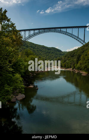 Eine große Stahlbrücke wölbt über den New River Gorge und den New River, in den Appalachen in der Nähe von Fayetteville, WV.  Die Brücke, Baujahr 1977, ist die größte Spannweite Stahlbrücke in der westlichen Hemisphäre und die dritte höchste in den USA.  Es erstreckt sich über den New River National River, Teil der US-Park-Service und ein beliebtes Ausflugsziel für Sparren und Kletterer. Stockfoto