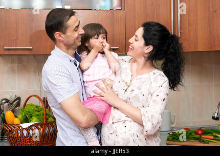 Familienbild in Küche Interieur mit frischem Obst und Gemüse, gesunde Ernährung Konzept, schwangere Frau, Mann und Kind Mädchen Stockfoto