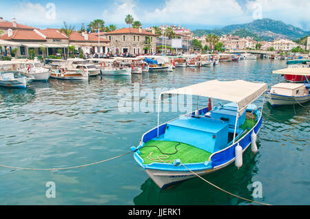 MARMARIS, Türkei - 10. Mai 2015: kleine Boote vertäut am Kanal im Zentrum von Marmaris mit Menschen sitzen an Restaurants in der Umgebung und die Berge am backgr Stockfoto