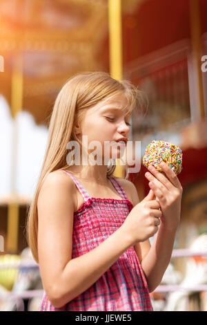 Niedliche kleine Mädchen essen Liebesapfel auf Messe im Vergnügungspark. Stockfoto