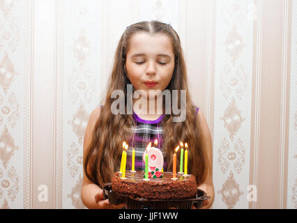 Mädchen bläst Kerzen auf ihrem Geburtstagskuchen Stockfoto