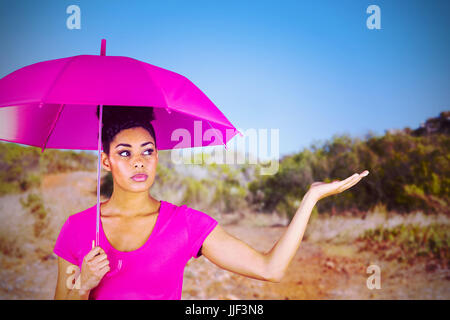 Junge Frau trägt rosa Regenschirm gegen Bergweg Stockfoto