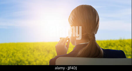 Rückansicht des Geschäftsfrau Zigarre an malerischen Blick auf gelben Senf Feld halten Stockfoto