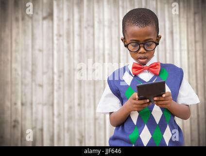 Digital Composite jungen in Weste und Fliege mit Rechner gegen verschwommen Holzplatte Stockfoto