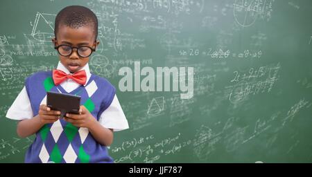 Digital Composite jungen in Weste und Fliege mit Rechner gegen grüne Tafel mit Mathe doodles Stockfoto