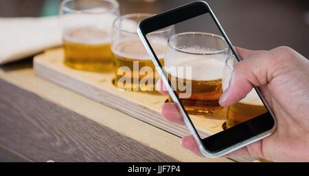 Digital Composite Hand fotografieren Biergläser durch Smartphone an Bar Stockfoto