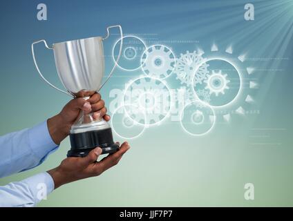 Digital Composite Digital zusammengesetztes Bild von Hand, die Trophäe gegen Zahnräder Stockfoto