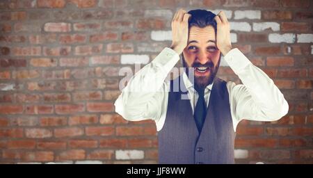 Digitalen Verbund aus besorgt Hipster Mann mit seinen Händen auf dem Kopf vor einer roten Wand Stockfoto