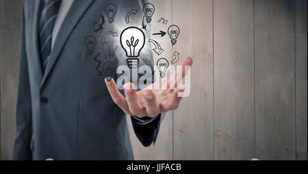Digital Composite der Geschäftsmann Mittelteil mit Glühbirne Kritzeleien und flare gegen graue Holzplatte Stockfoto