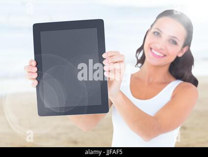 Digital Composite Smiling Frau mit Tablette gegen verschwommen Strand mit Flair Stockfoto