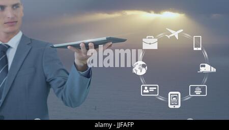 Digital Composite Geschäftsmann Holding Tablet mit Geschäft Symbolen gegen weichen grauen Himmel mit Sonnenschein Stockfoto