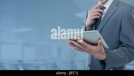 Digital Composite Geschäftsmann Holding Tablette im blauen Fabrik Tagungsbüro Stockfoto