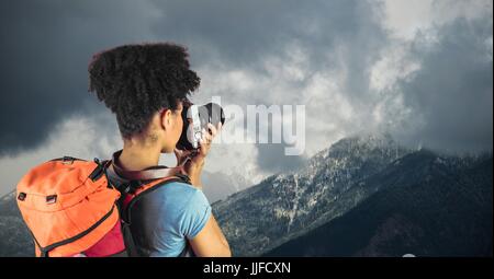 Digitalen Verbund aus Rückansicht des Hipster Berge gegen bewölktem Himmel zu fotografieren Stockfoto