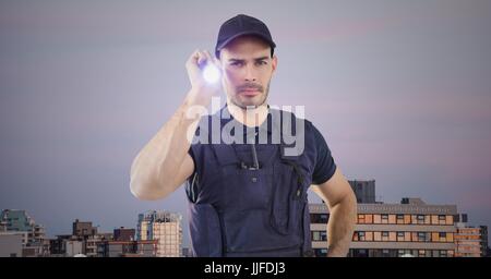 Digital Composite Wachmann mit Taschenlampe gegen Gebäude und lila Himmel Stockfoto