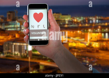 Bild von Hand mit Smartphone gegen beleuchtete Gebäude Stadt beschnitten Stockfoto