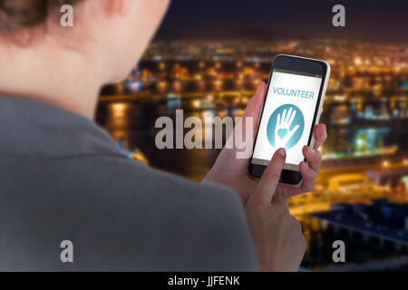 Nahaufnahme der Geschäftsfrau mit Handy gegen beleuchteten Hafen gegen Stadtbild Stockfoto