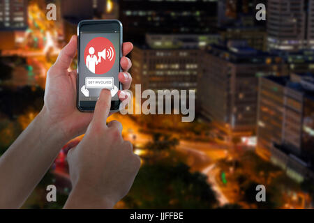 Abgeschnitten von Hand mit Handy gegen beleuchtete Straßen von Gebäuden in der Stadt Stockfoto