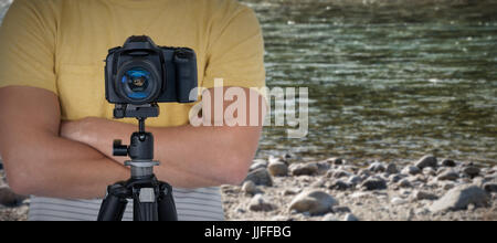 Digitale Kamera auf Stativ gegen Fotografen gegen Felsen am Ufer Stockfoto