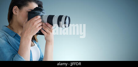 Junge weibliche Fotografen fotografieren durch Digitalkamera gegen graue vignette Stockfoto