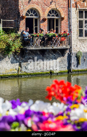 Touristen, die draußen zu sitzen, ein Restaurant / bar ist Balkon über dem Wasser des Flusses Leie / Lys in der alten Stadt von Gent / Gent, Ostflandern, Belg Stockfoto