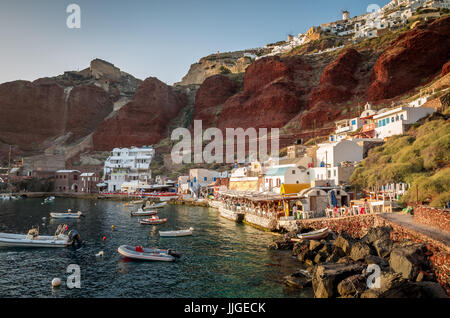 Amoudi, Santorin, Griechenland. Amoudi Bay befindet sich unter Dorf Oia. Boote und Tavernen in der Nähe des Wassers. Stockfoto