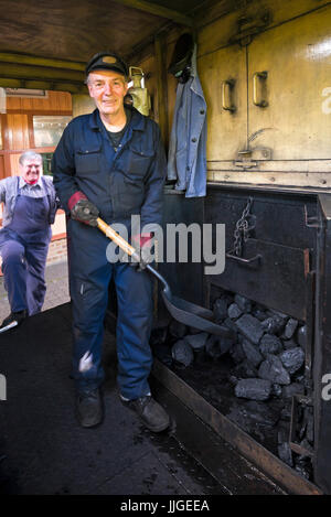 Vertikale Porträt ein Feuerwehrmann auf dem Führerstand einer Dampflok stehen. Stockfoto