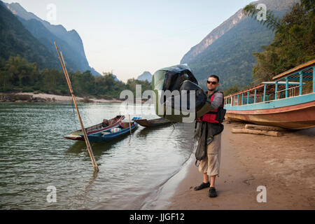 Robert Hahn entlüftet sein Packraft am Ufer des Nam Ou Fluß in Muang Ngoi, Laos am Ende eines langen Tages paddeln. Stockfoto