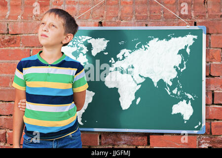 Meditative junge in der Nähe von Tafel mit Zeichnung Erdkarte in der improvisierten Outdoor-Klasse Stockfoto