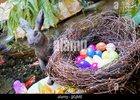 Ein Stein Osterhase saß ein Nest von gefärbten Eiern. Stockfoto