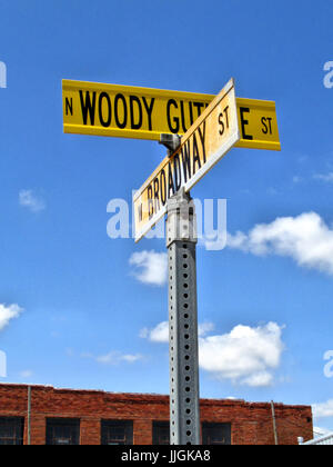 Die Straßenschilder Woody Guthrie Street / Broadway stehen in der Innenstadt von Okemah, Oklahoma. Stockfoto