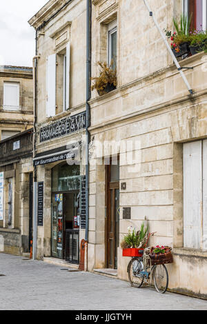 Alten altmodischen blaue Dame Fahrrad mit flachen Reifen gegen eine Wand von einem städtischen Käse und Wein-Shop, Pauillac, Gironde, Nouvelle-Aquitaine Frankreich geparkt Stockfoto