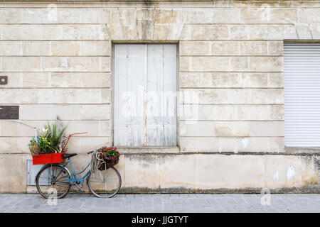 Alten altmodischen blaue Dame Fahrrad mit flachen Reifen geparkt lehnt gegen eine Wand, Pauillac, Gironde Abteilung, Nouvelle-Aquitaine, Südwestfrankreich Stockfoto