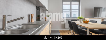 Stilvolle Küche mit Waschbecken lange Arbeitsplatte und Essbereich in modernen Wohnung Panorama Stockfoto