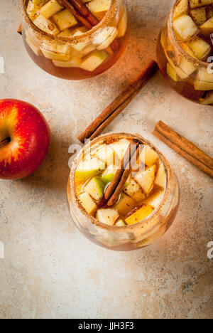 Herbst- und Getränke. Warme Apfel Sangria, Apfelwein mit Zucker, Zimt, Früchte und Gewürze. In Gläsern, auf einem Stein Beige Tisch. Mit der Stockfoto