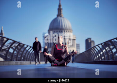 Eine Frau, die Meditation über die Millennium Bridge mit St. Pauls Kathedrale im Hintergrund. Stockfoto
