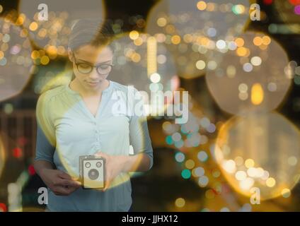 Fotograf mit Vintage-Kamera fotografieren. Verschwommene Stadt Lichter Hintergrund und gelbe verschwommene l Stockfoto
